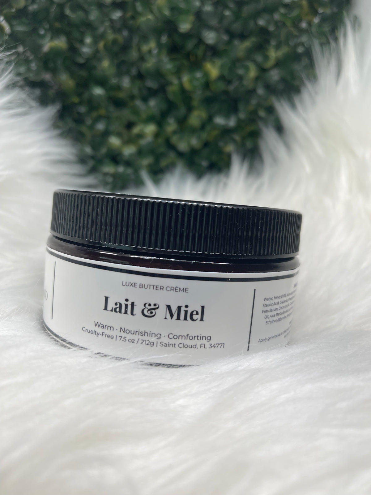 Jar of Lait & Miel cream on a fluffy white surface with greenery in the background