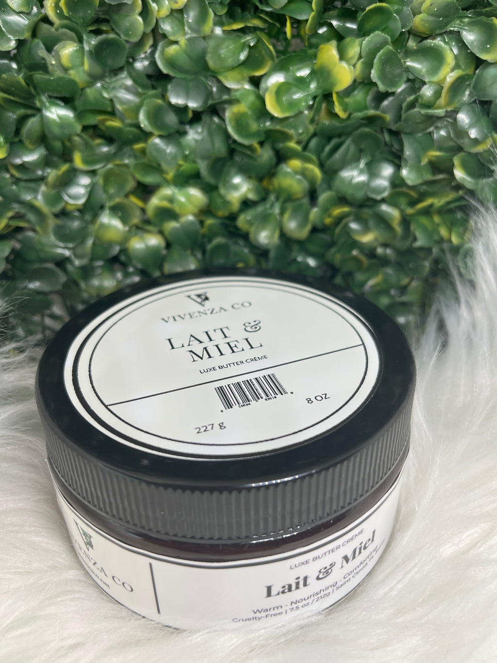 Jar of VIVENZA Co. product on a textured white surface with green leaves in the background