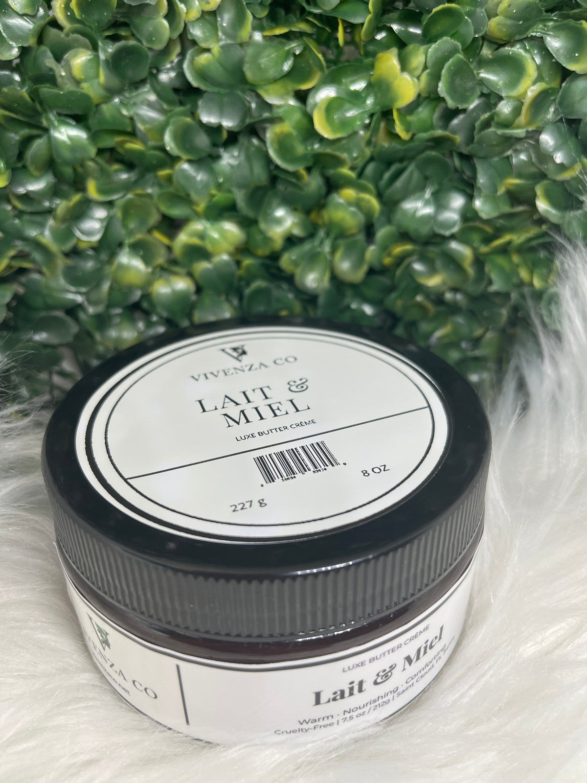 Jar of VIVENZA Co. product on a textured white surface with green leaves in the background