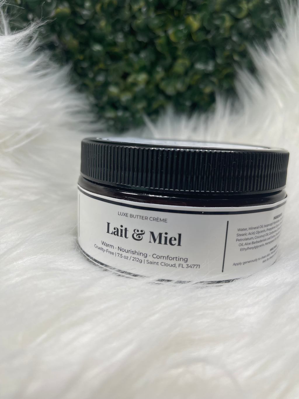 Jar of Lait & Miel cream on a fluffy white surface with greenery in the background