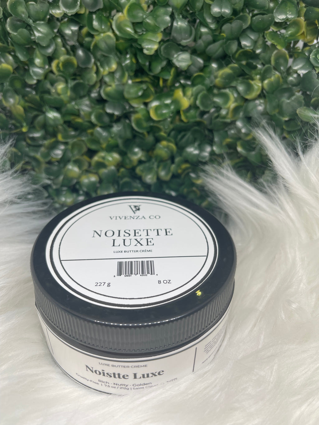 Jar of Noisette Luxe on a green leafy background