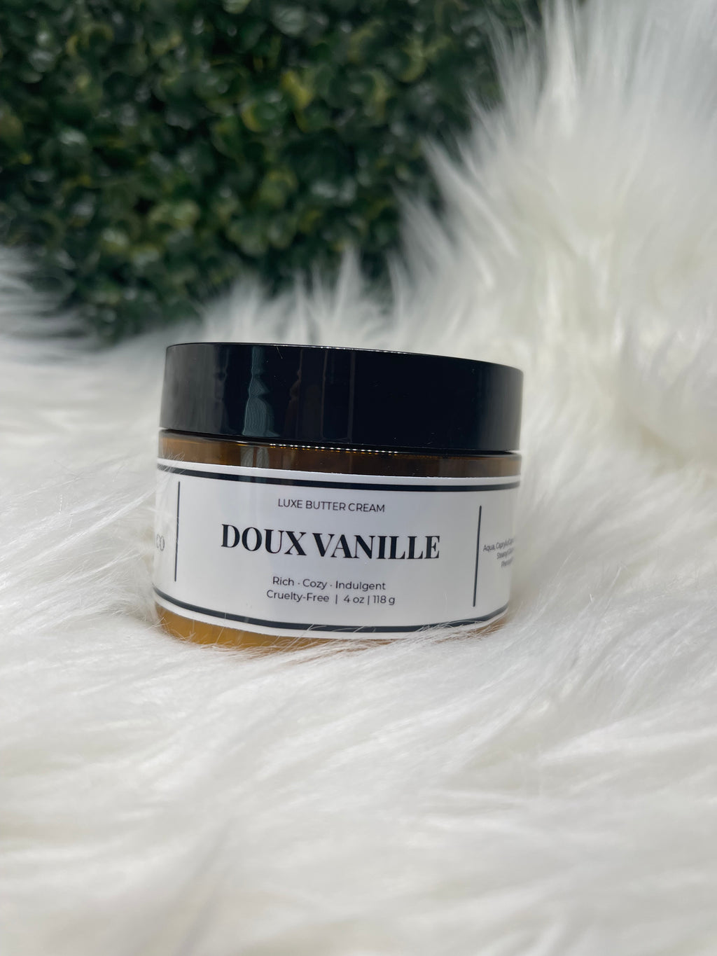 Jar of Doux Vanille cream on a white fur surface with greenery in the background