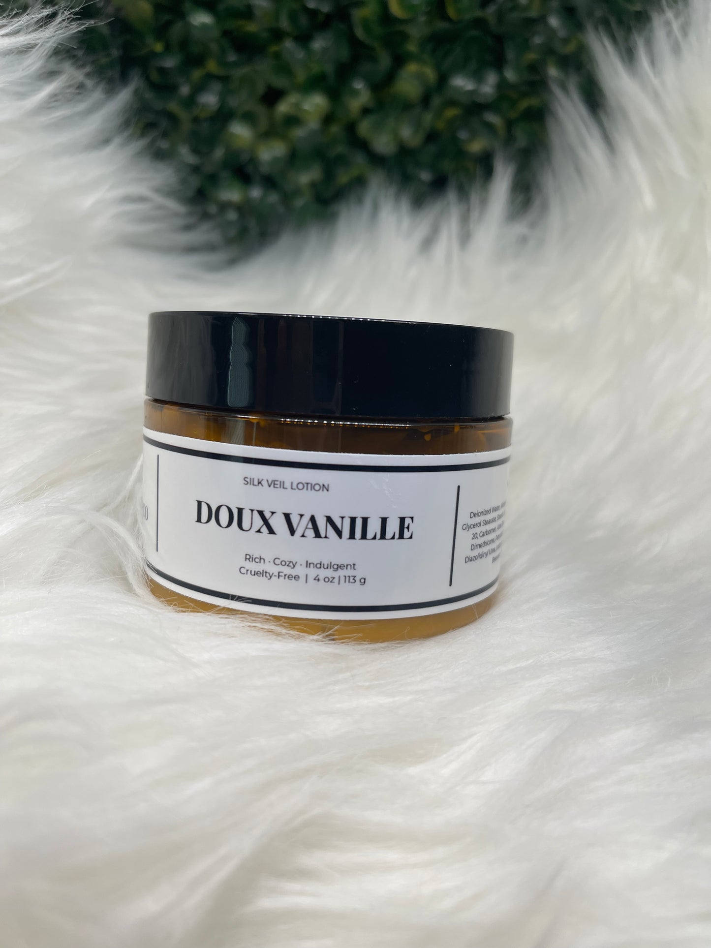 Cosmetic jar with 'DOUX VANILLE' label on a white fur surface