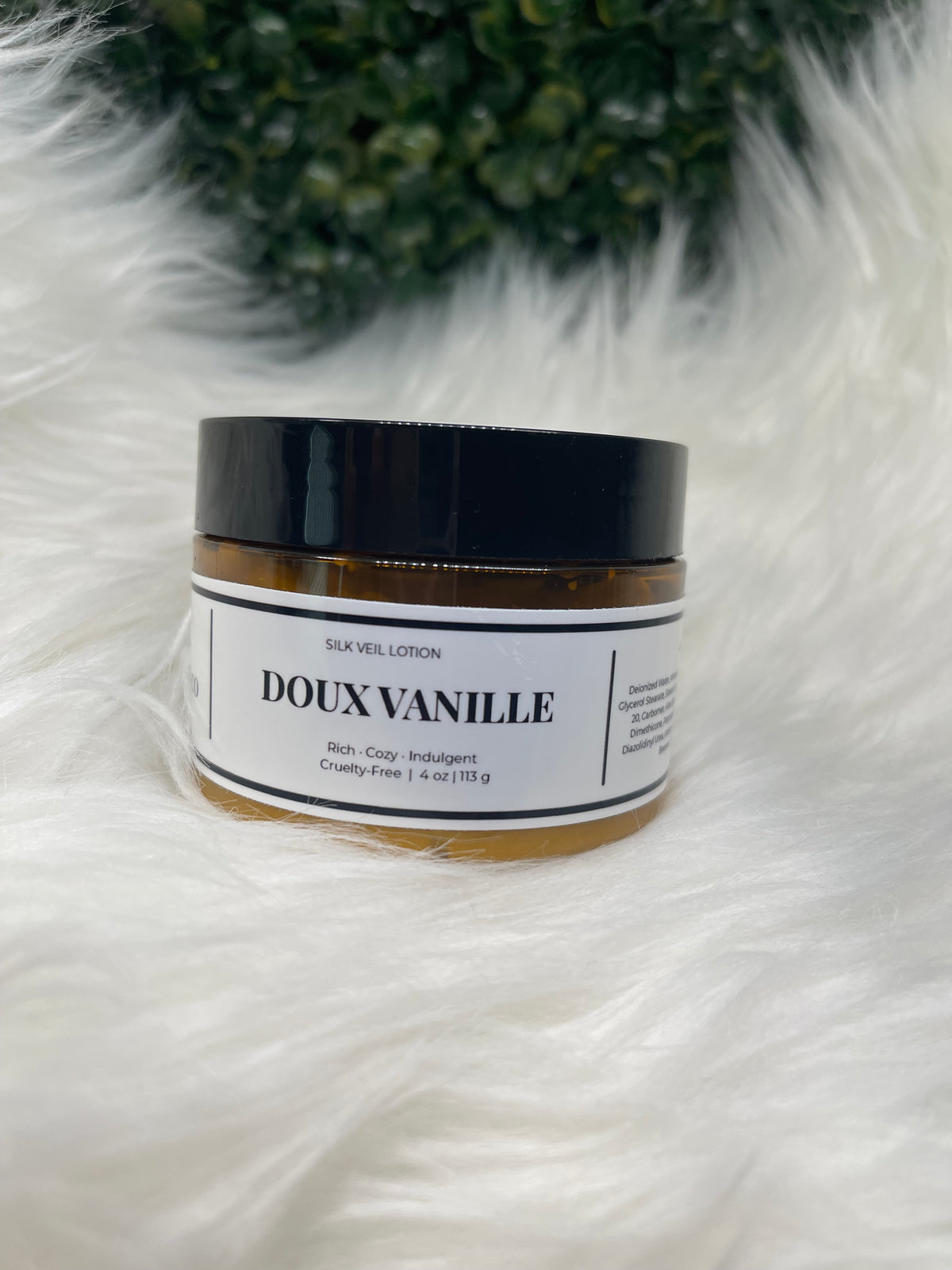 Cosmetic jar with 'DOUX VANILLE' label on a white fur surface