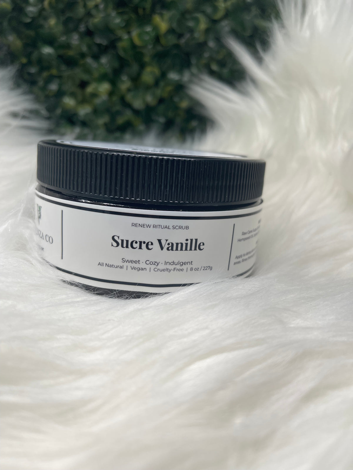 Jar of Sucre Vanille on a white fluffy surface with greenery in the background