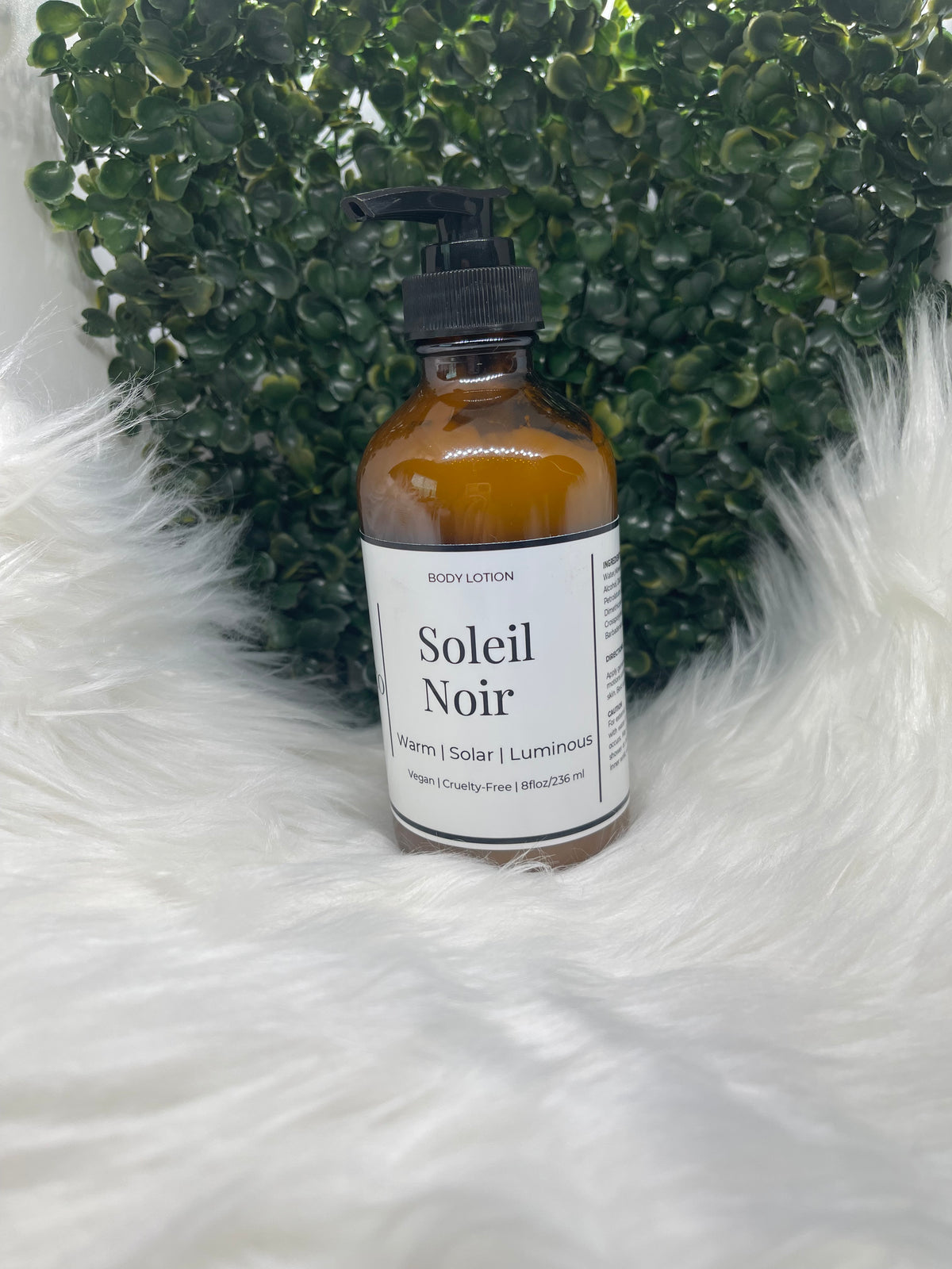 Bottle of Soleil Noir hair product on a textured white surface with green stones.