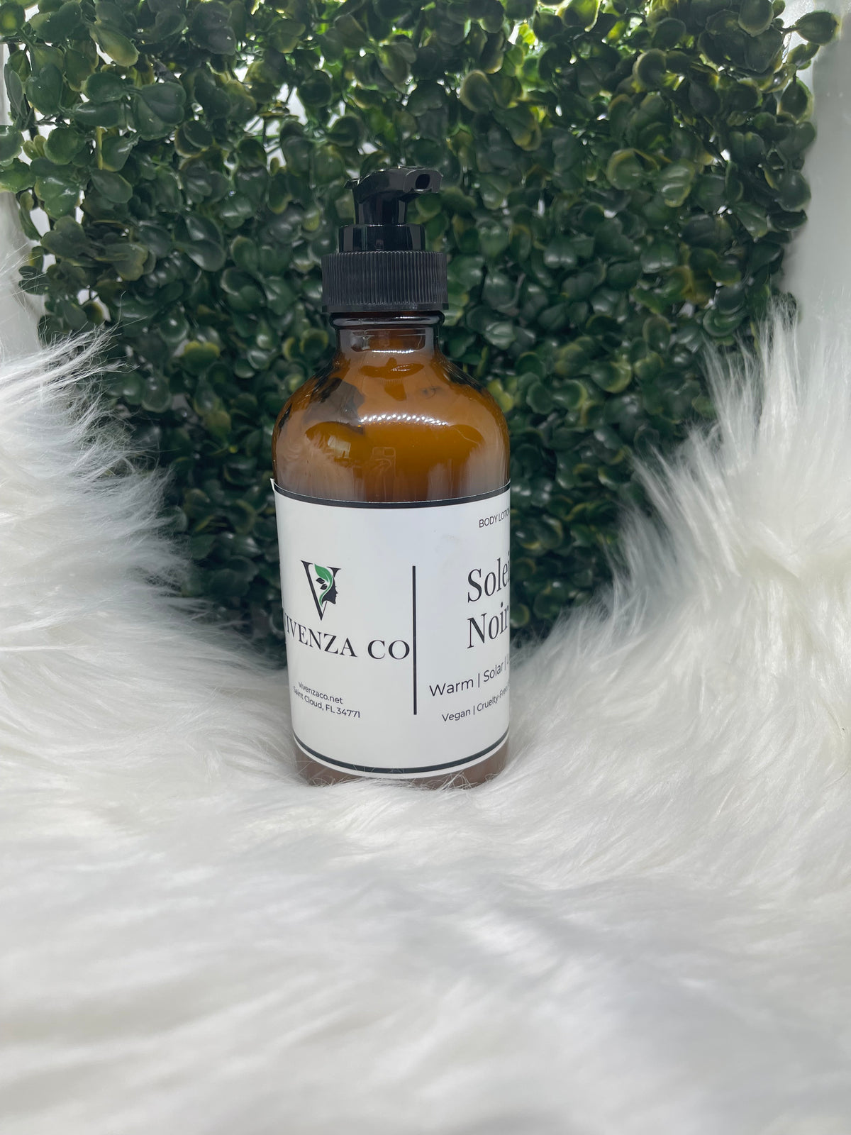 Bottle of VIVENZA Co. product on a textured white surface with green leaves